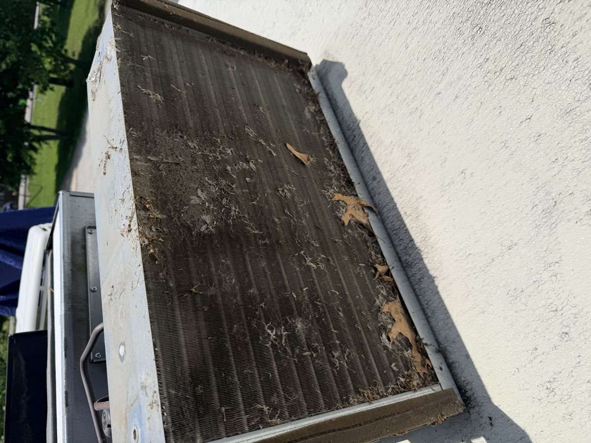 RV air conditioner condenser coil before cleaning — clogged with leaves and debris